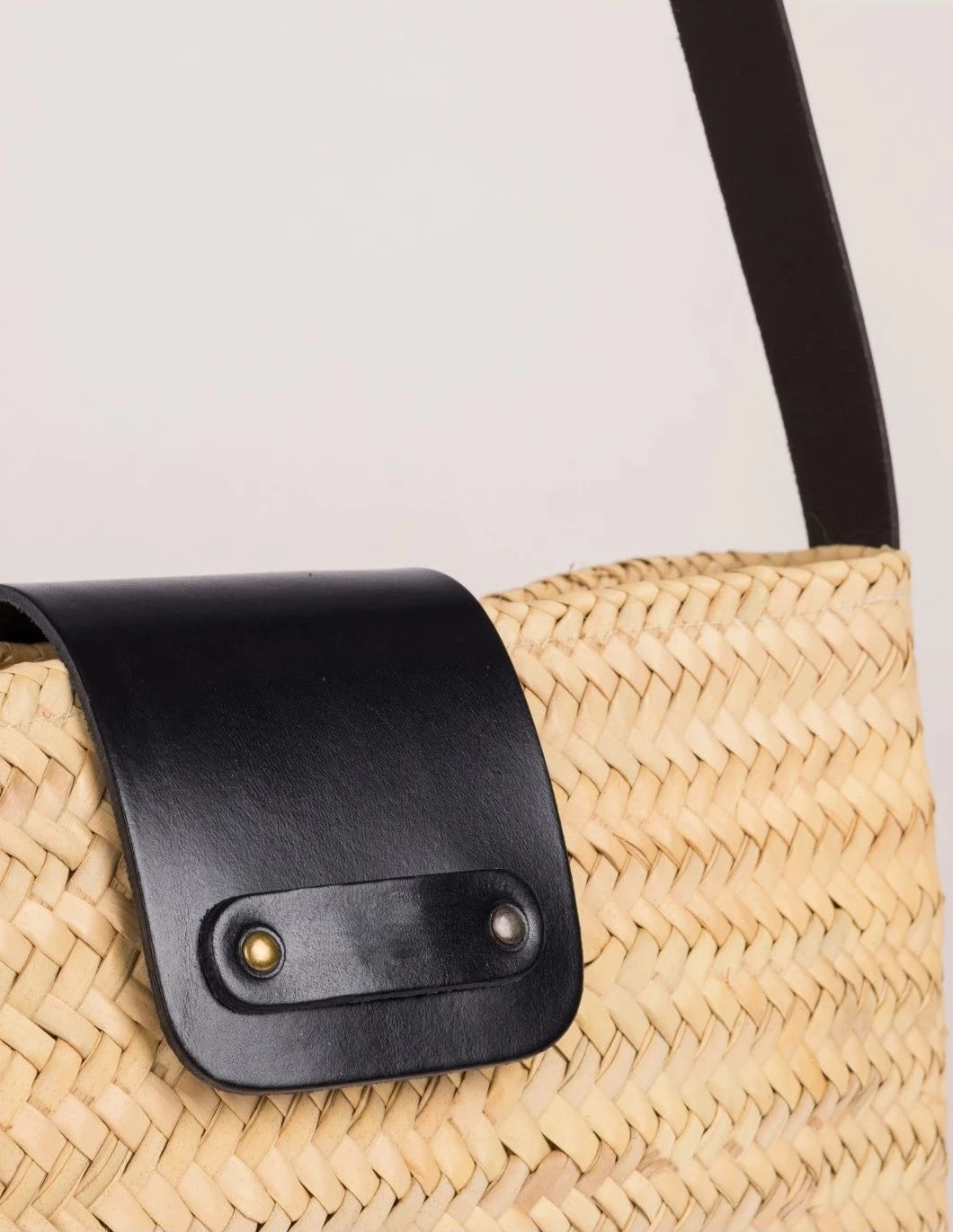 Close-up of the black calfskin front flap with twin rivets on the Asmae Baguette Bag