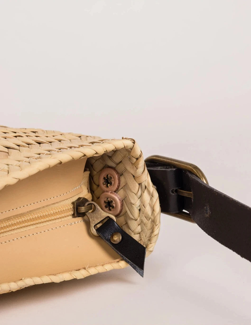 Open zip-top view of the black-trimmed Asmae palm leaf baguette bag showing the woven interior