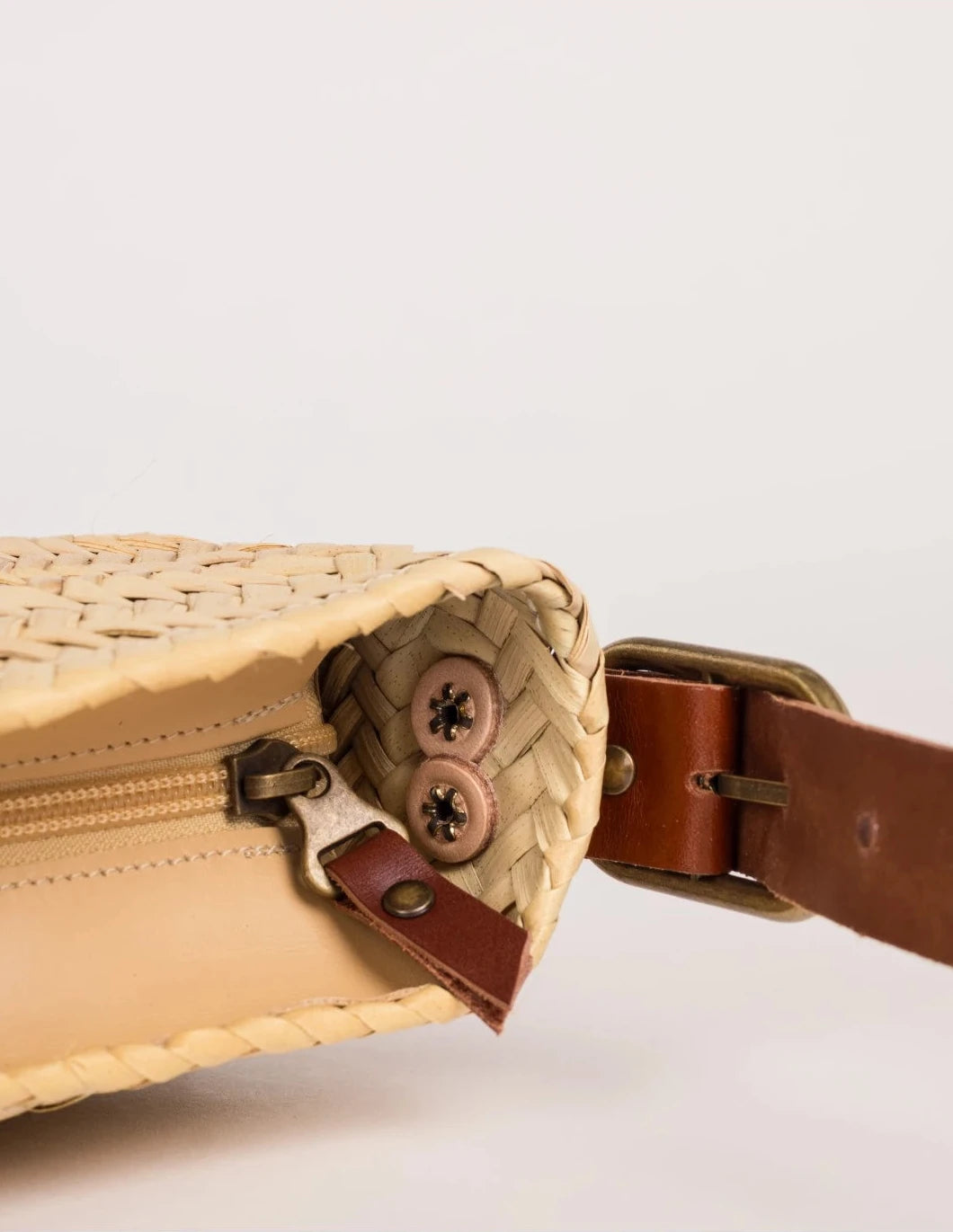 Open zip-top view of the dark brown-trimmed Asmae palm leaf baguette bag showing the woven interior