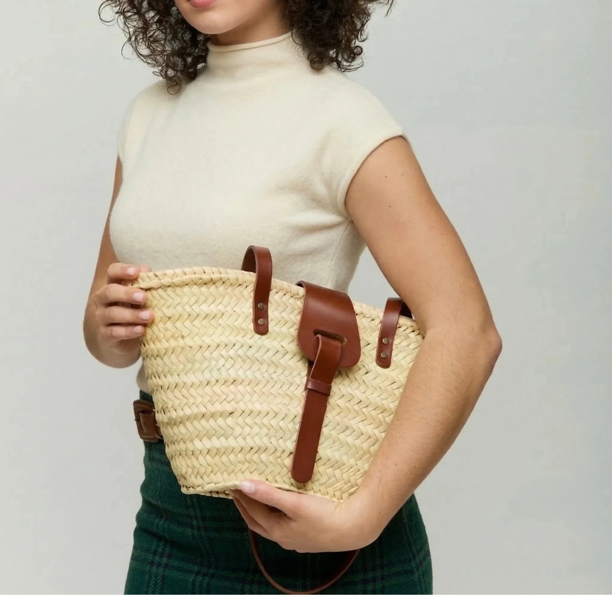 Woman carrying the Fadma Small palm leaf basket bag in dark brown calfskin on the shoulder