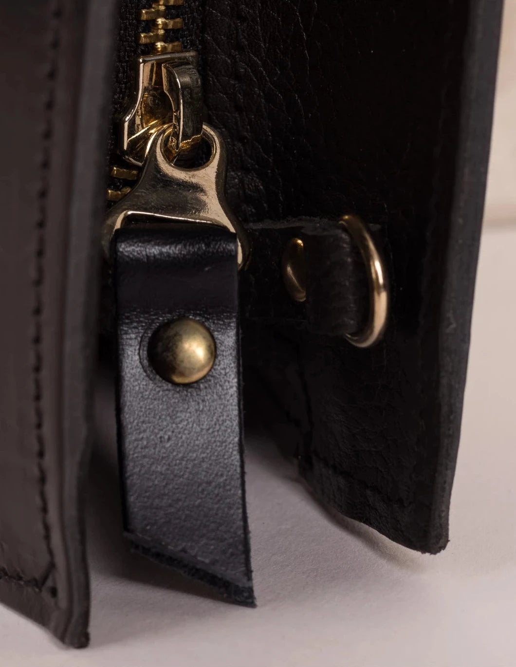 Close-up of the antique brass clasp and black leather trim on the Lamia Cane Clutch