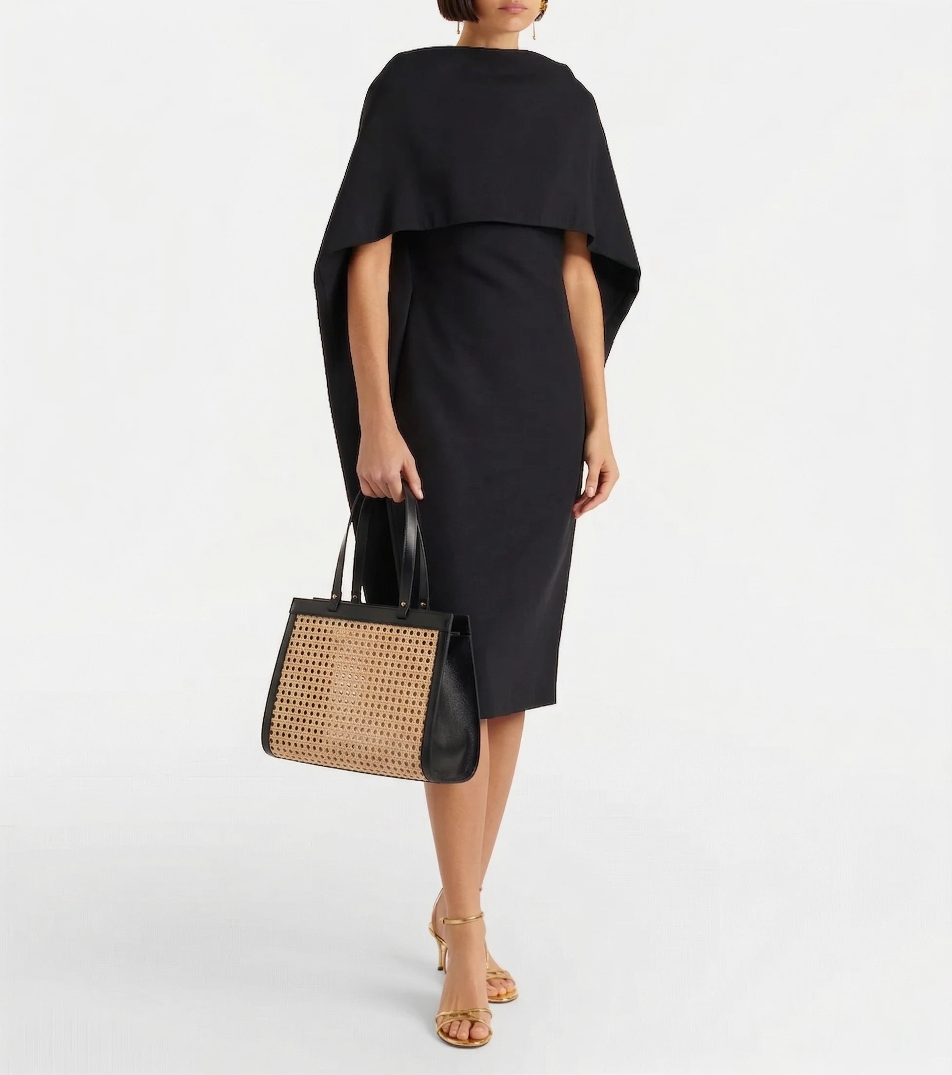 Lamia Cane Tote carried by the handles, shown with a black dress, full-length