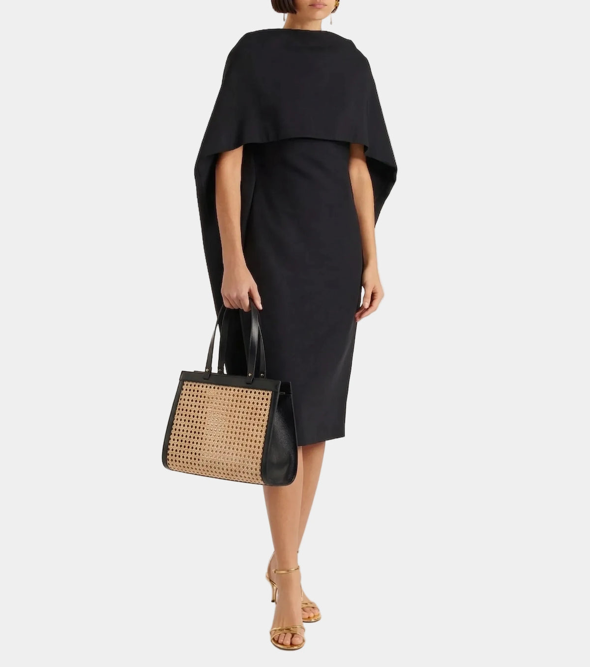 Lamia Cane Tote carried by the handles, shown with a black dress, full-length #color_black