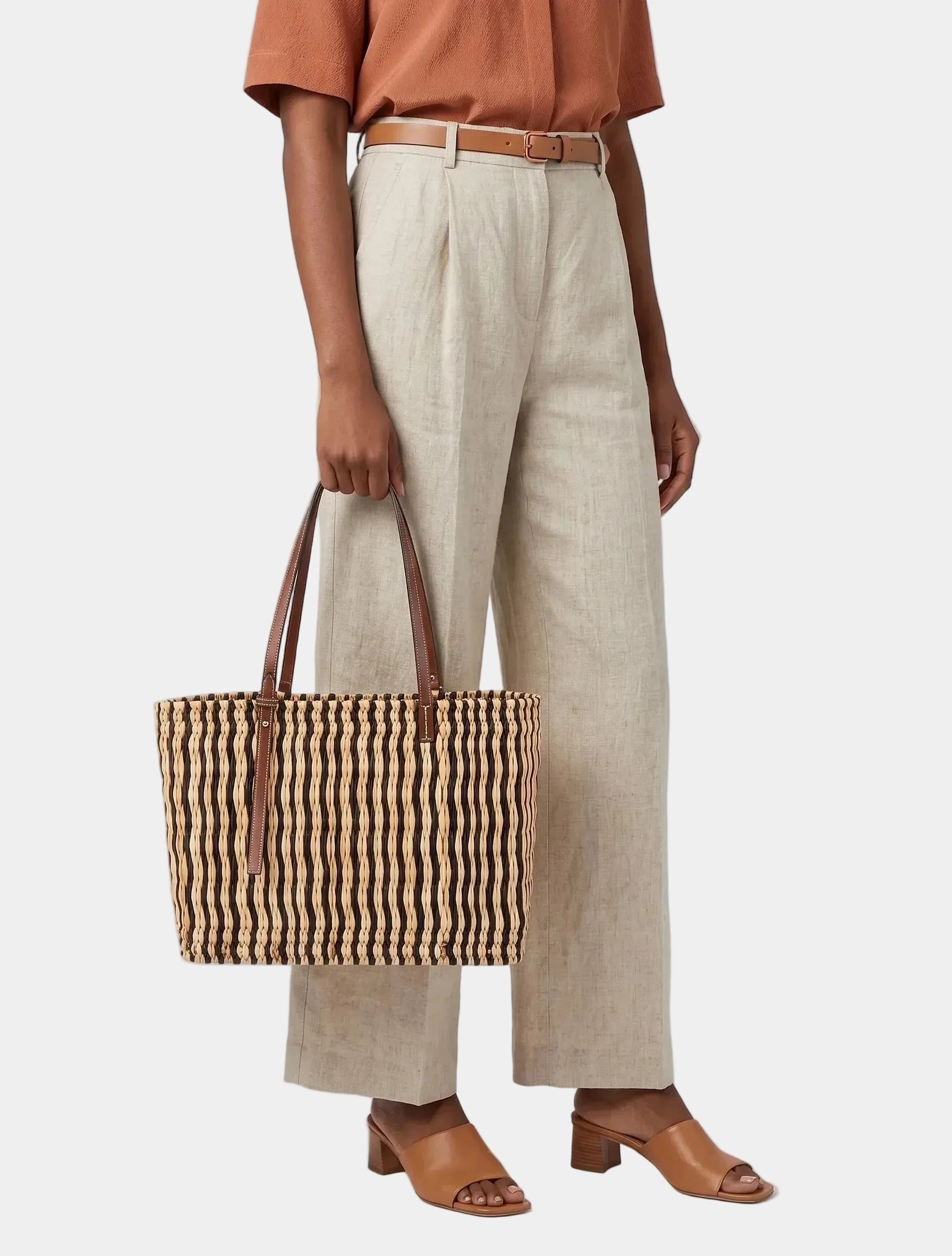 Model carrying MARRAVIE Ghita dark brown striped basket tote in hand