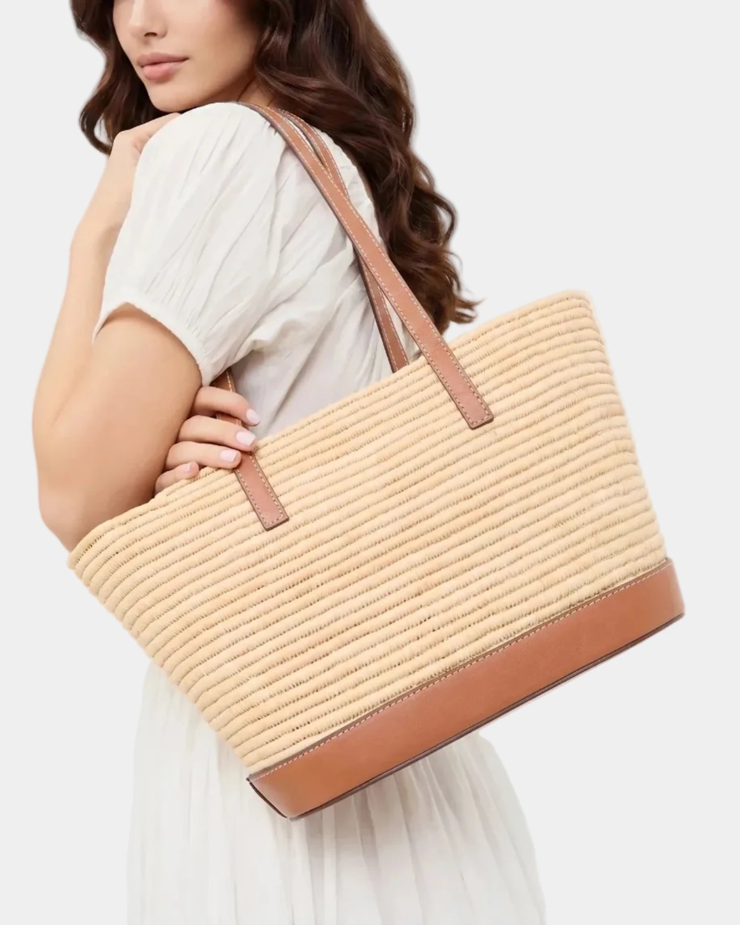 Woman in a white dress carrying the Salma raffia basket tote on her shoulder