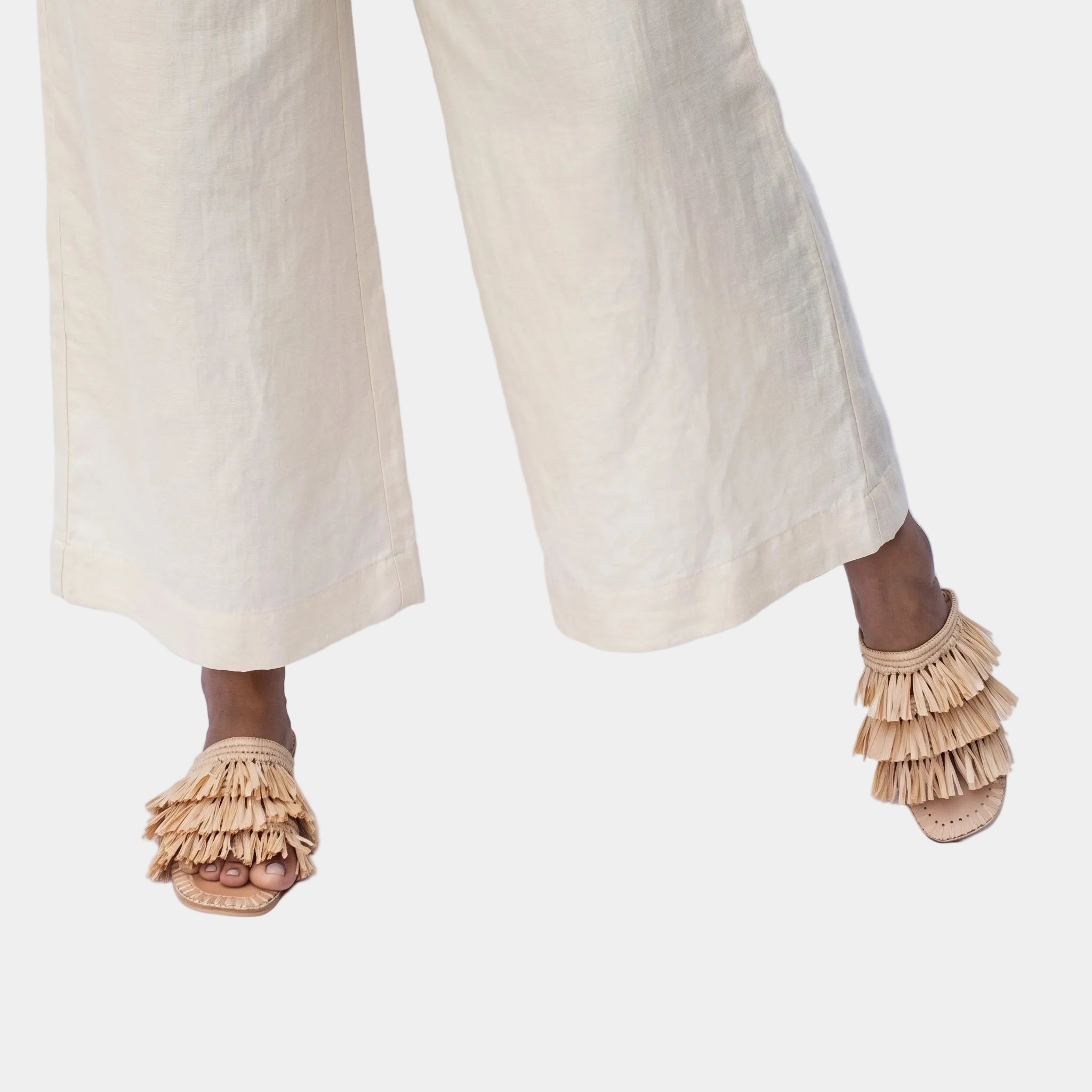 Woman in cream trousers wearing natural raffia fringe slide sandals — Silya slide by MARRAVIE