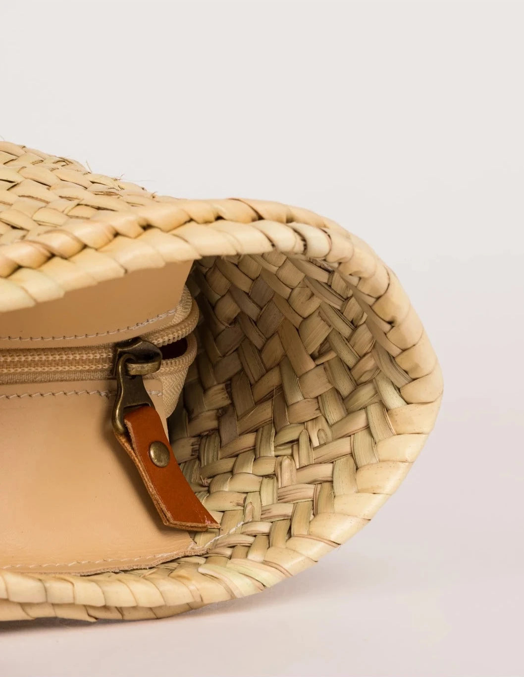 Interior view of Aicha palm leaf basket bag with zip closure and light brown leather trim