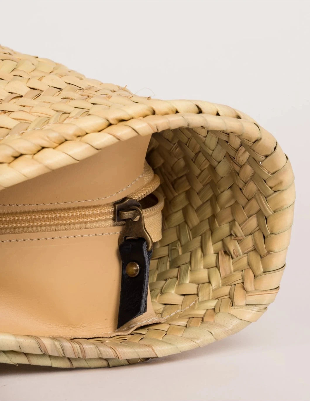 Interior view of Aicha handwoven palm leaf basket bag with zip closure and leather trim