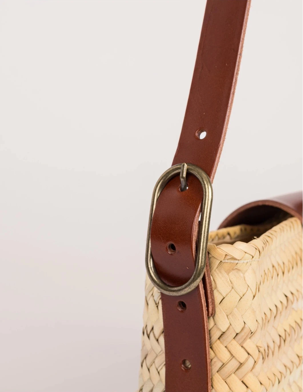 Antique brass buckle on the adjustable dark brown calfskin strap of the Asmae Baguette Bag