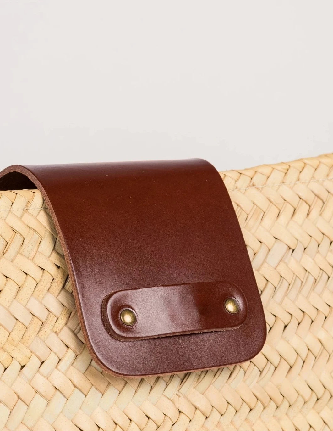 Close-up of the dark brown calfskin front flap with twin rivets on the Asmae Baguette Bag