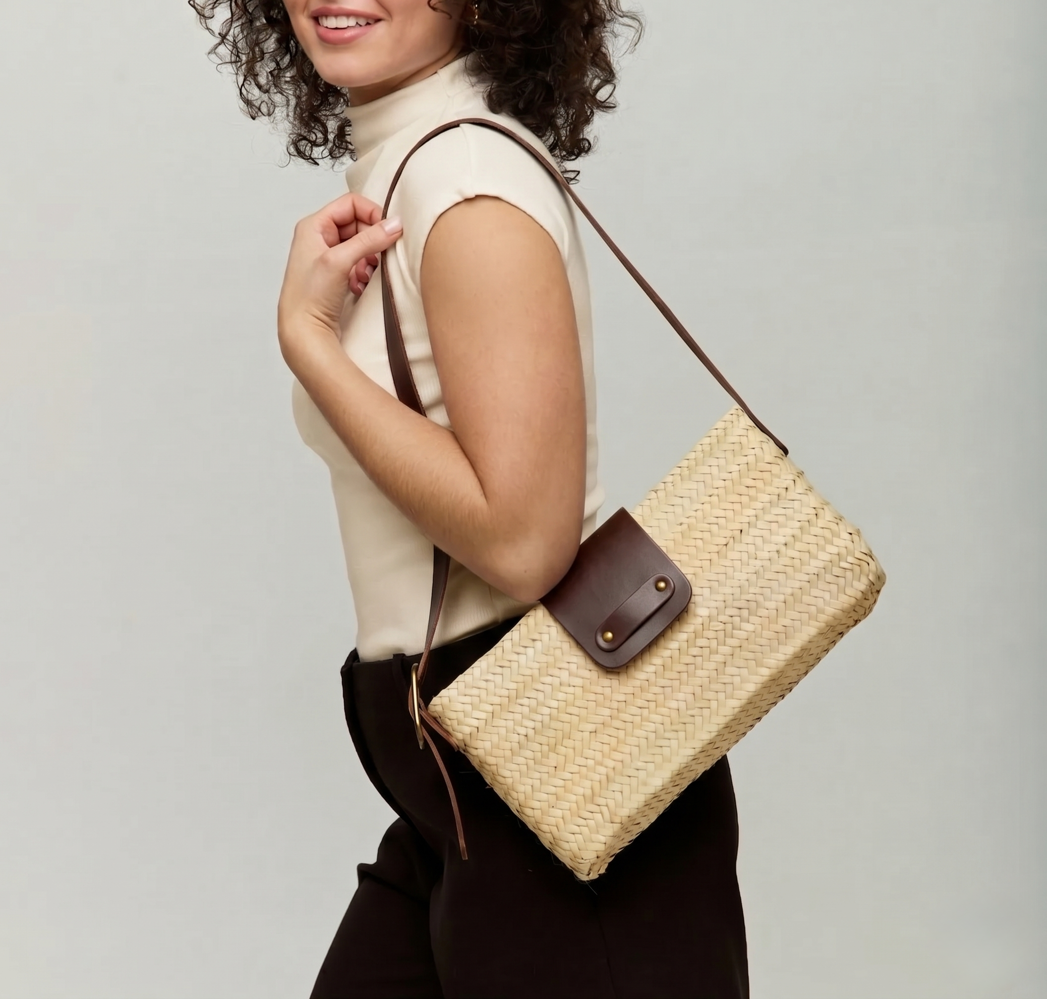Asmae Baguette Bag worn on the shoulder in handwoven palm leaf with dark brown calfskin strap and flap