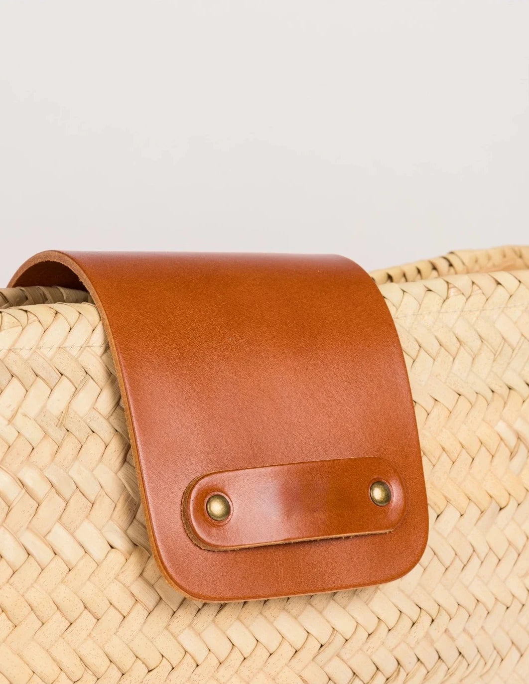 Close-up of the light brown calfskin front flap with twin rivets on the Asmae Baguette Bag