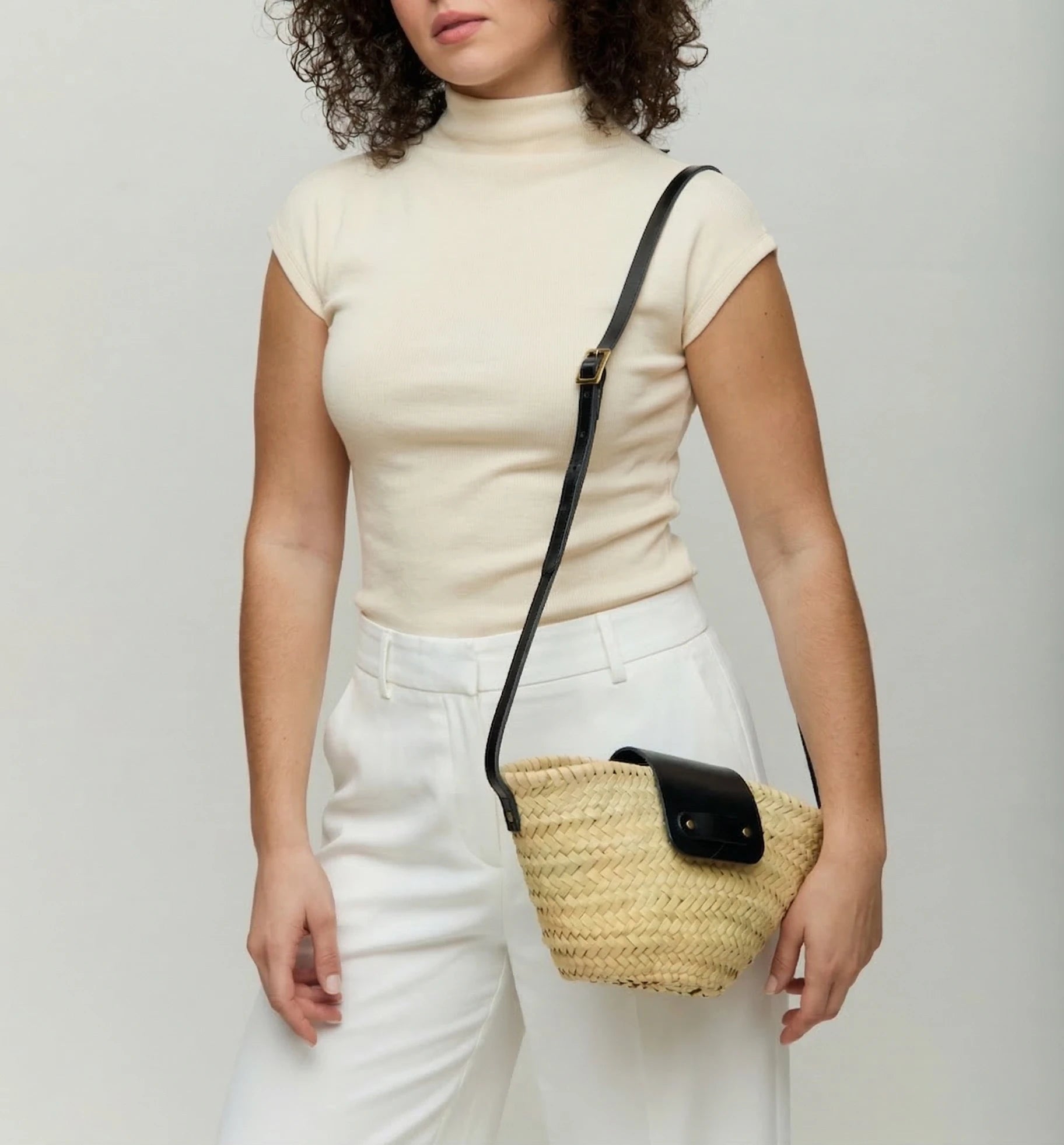 Woman wearing the Dija Crossbody palm leaf basket bag in black calfskin across the body