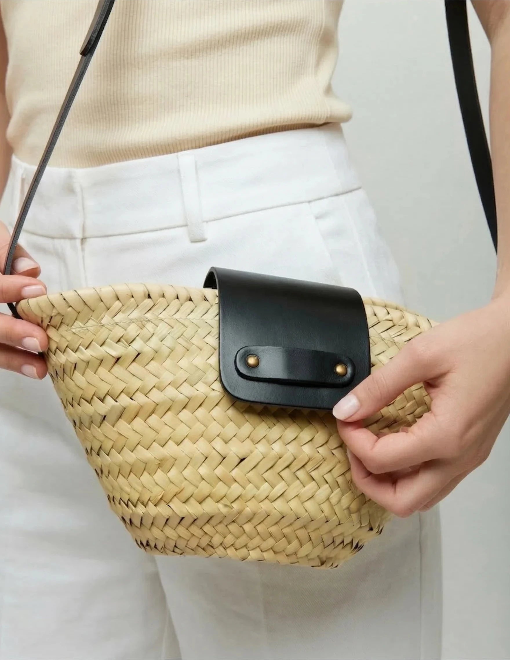 Woman wearing the Dija Crossbody palm leaf basket bag in black calfskin across the body