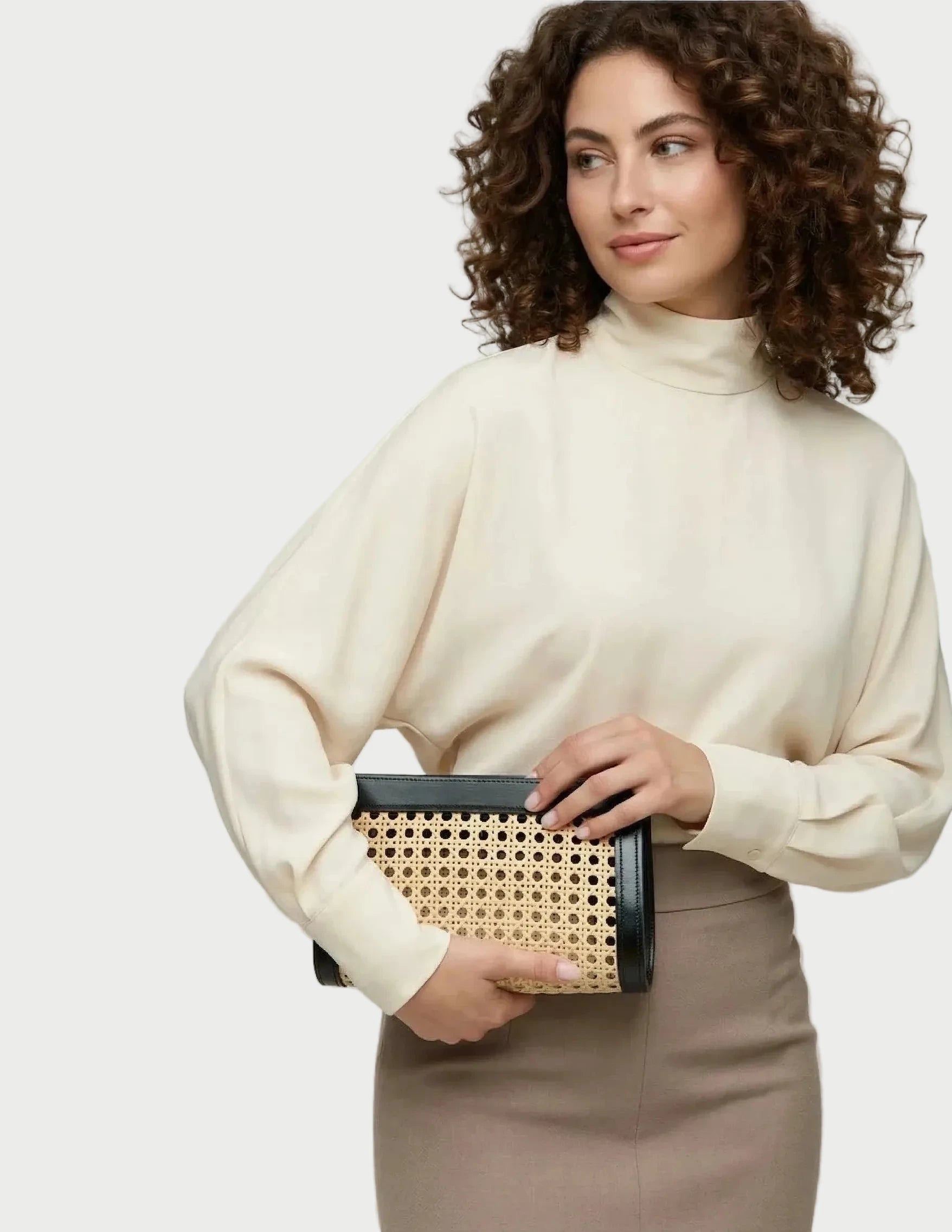 Lamia Cane Clutch held in hand, shown with a cream knit and tan skirt.