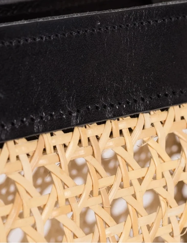Close-up of the black calfskin handles and leather frame on the Lamia Cane Tote #color_black