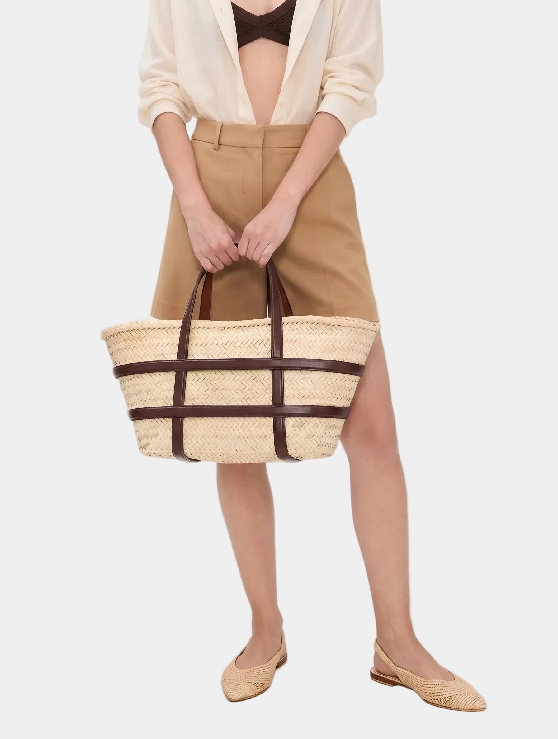 Model carrying Malika dark brown leather basket tote with tan trousers and flats