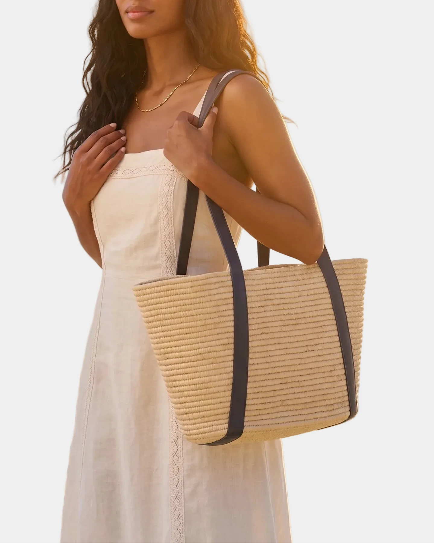 Woman carrying the Kenza raffia basket tote at the beach at sunset