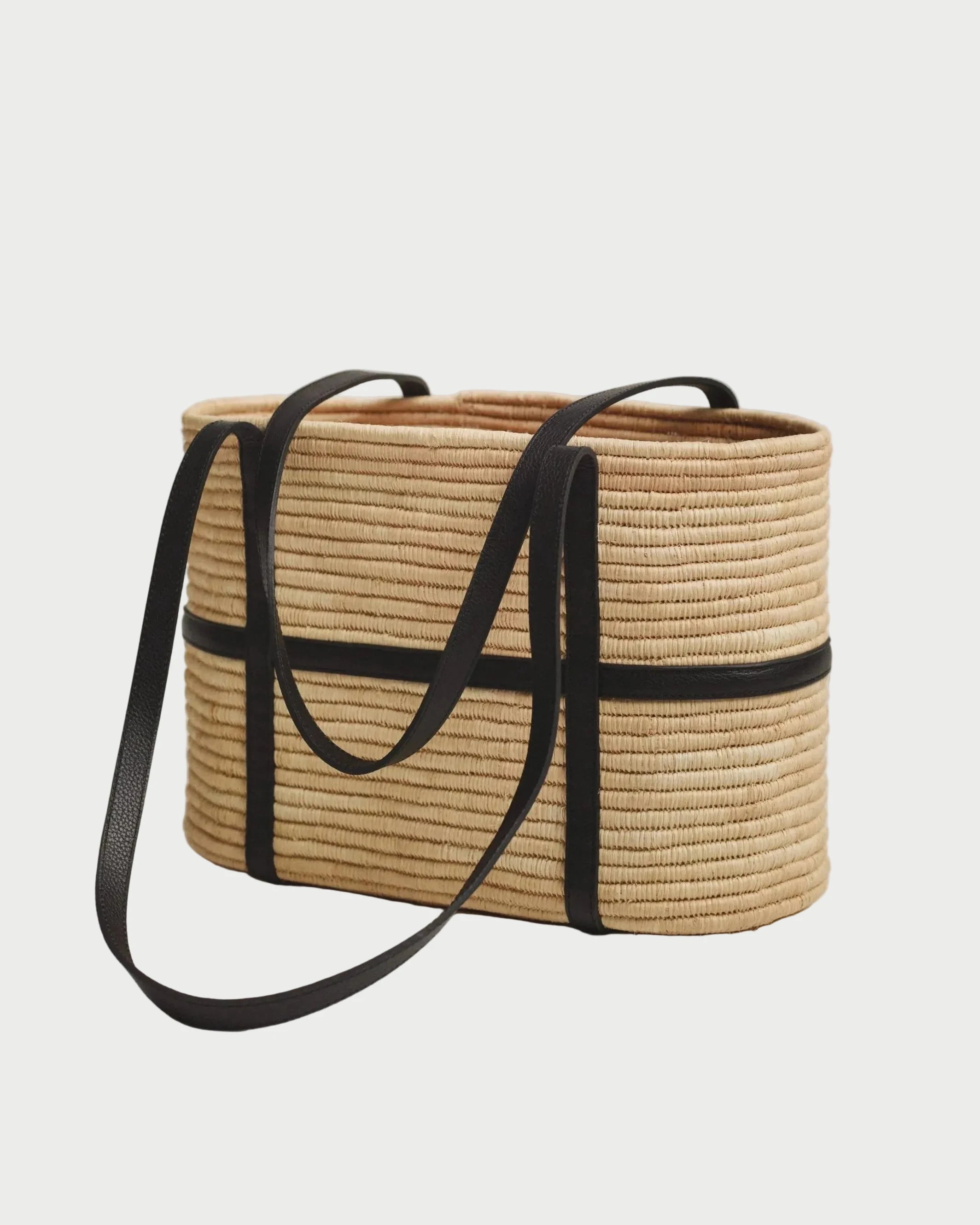 Side view of Kenza structured raffia tote showing black leather strap wrap and closed weave