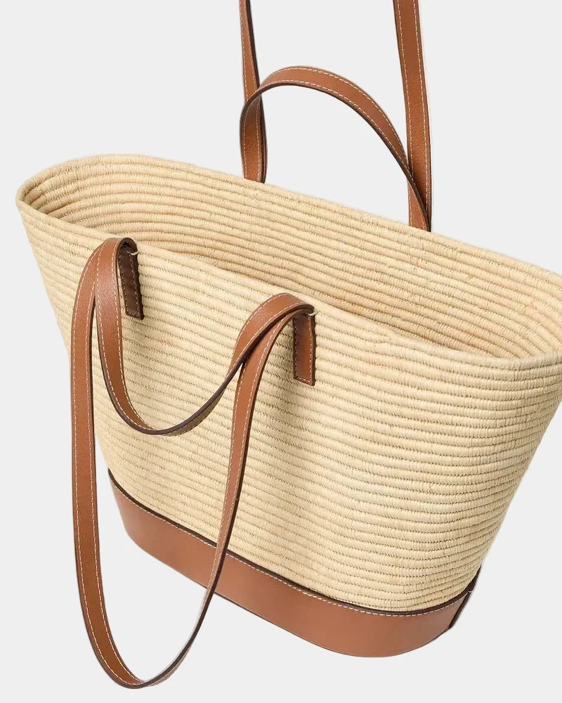 Raffia basket tote showing short top handles and longer shoulder straps for two-way carry