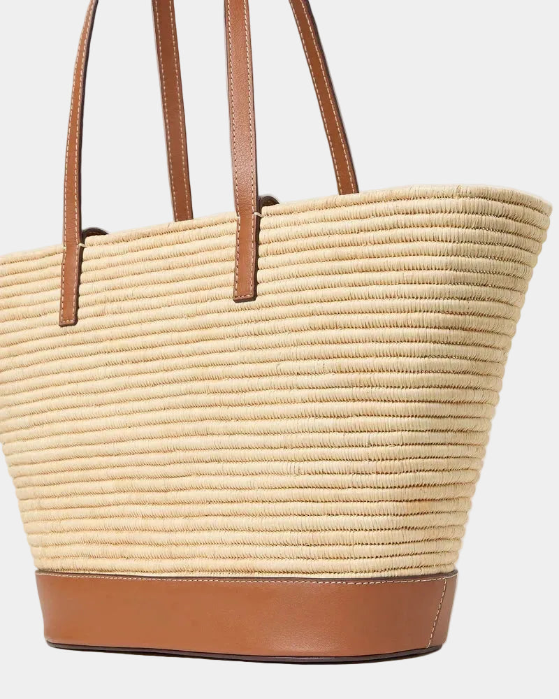 Raffia basket tote with cognac leather base shown at a three-quarter angle
