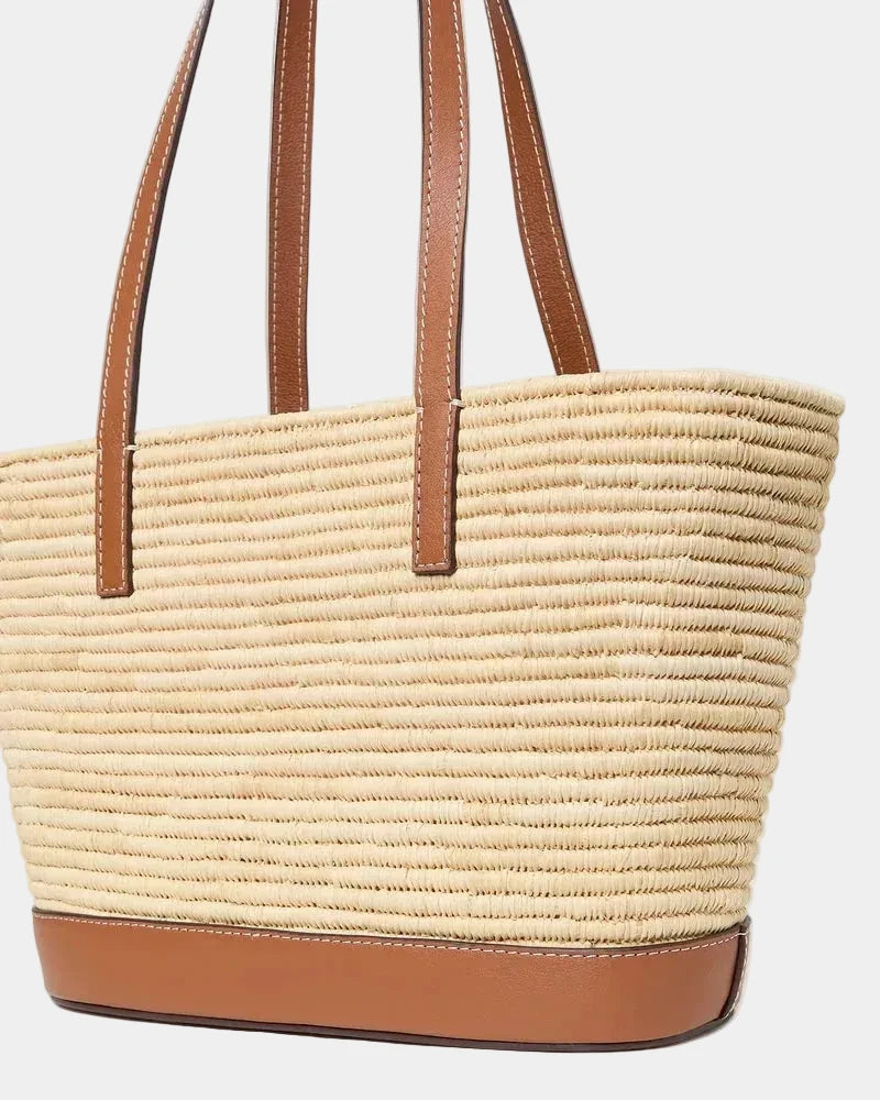 Raffia basket tote with cognac leather base shown at a three-quarter angle