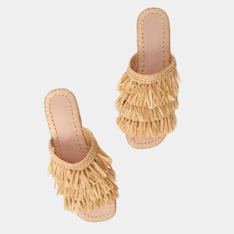 Pair of raffia fringe slides shown at an angle with hand-knotted tiers — Silya sandal by MARRAVIE