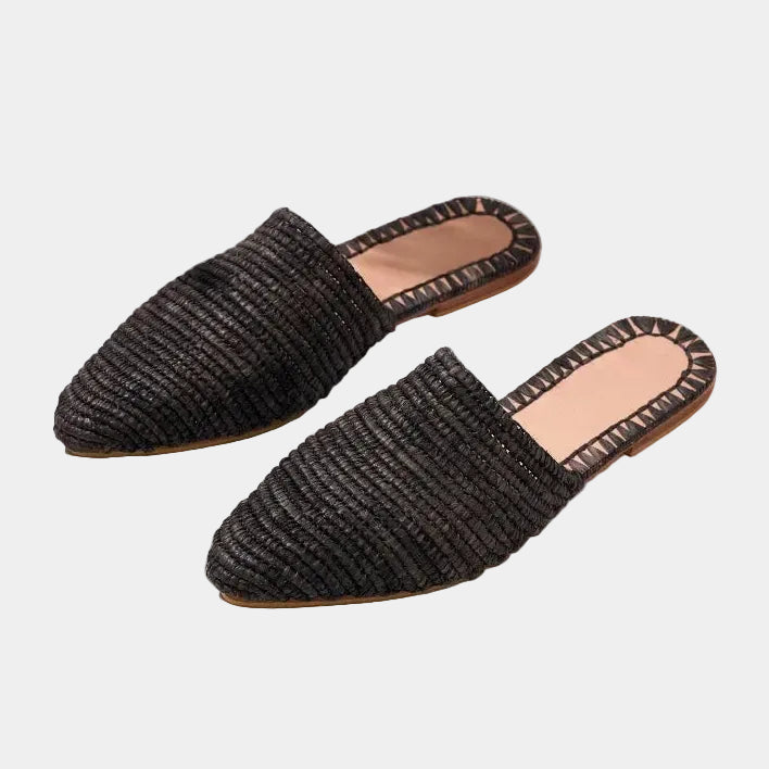 Pair of black raffia babouche mules with pointed toe, handwoven texture — Tilila mule in Black by MARRAVIE