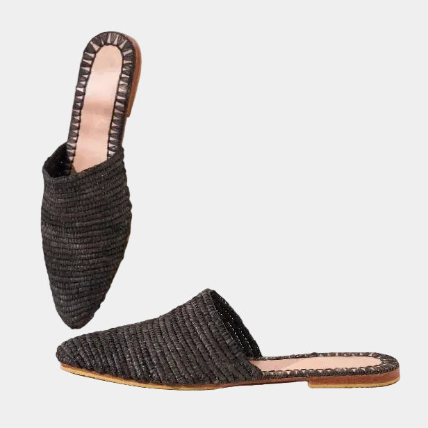 Black raffia babouche mules styled on white stone blocks — Tilila mule by MARRAVIE