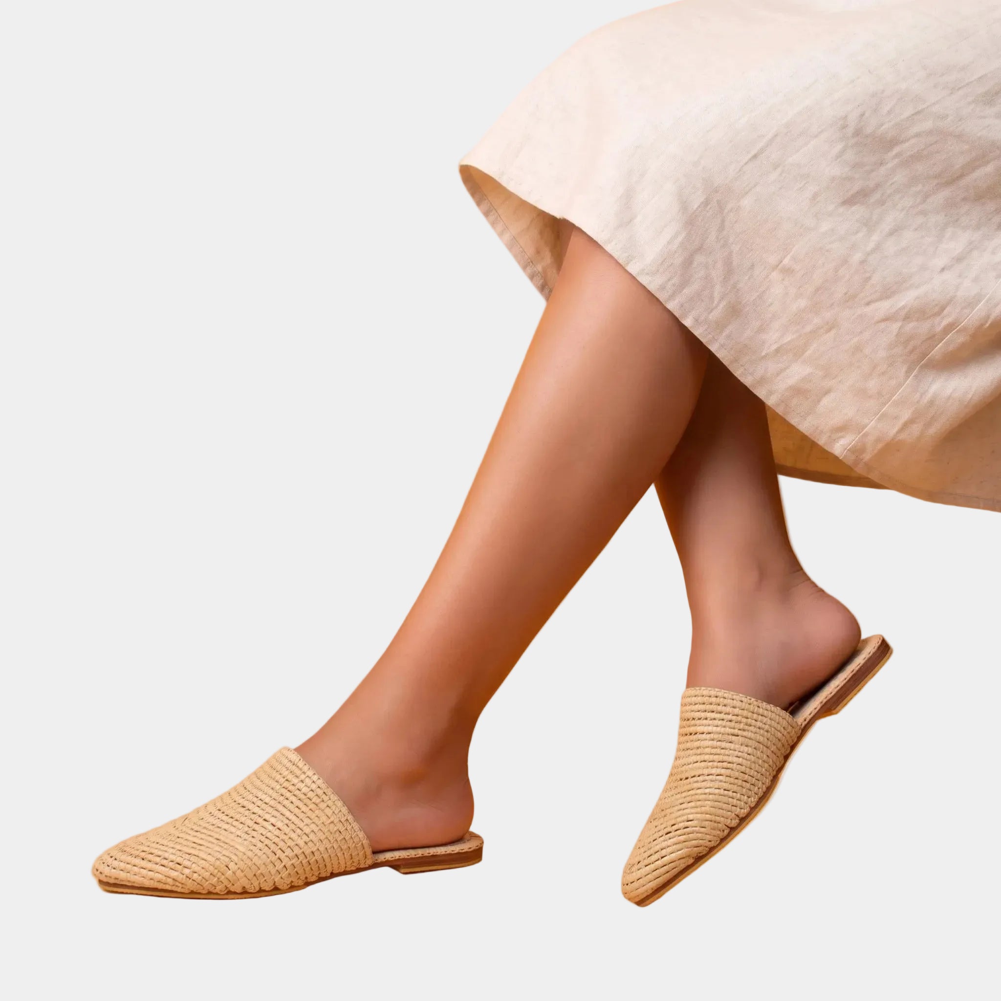 Woman wearing natural raffia babouche mules with a linen dress — Tilila slip-on mule by MARRAVIE
