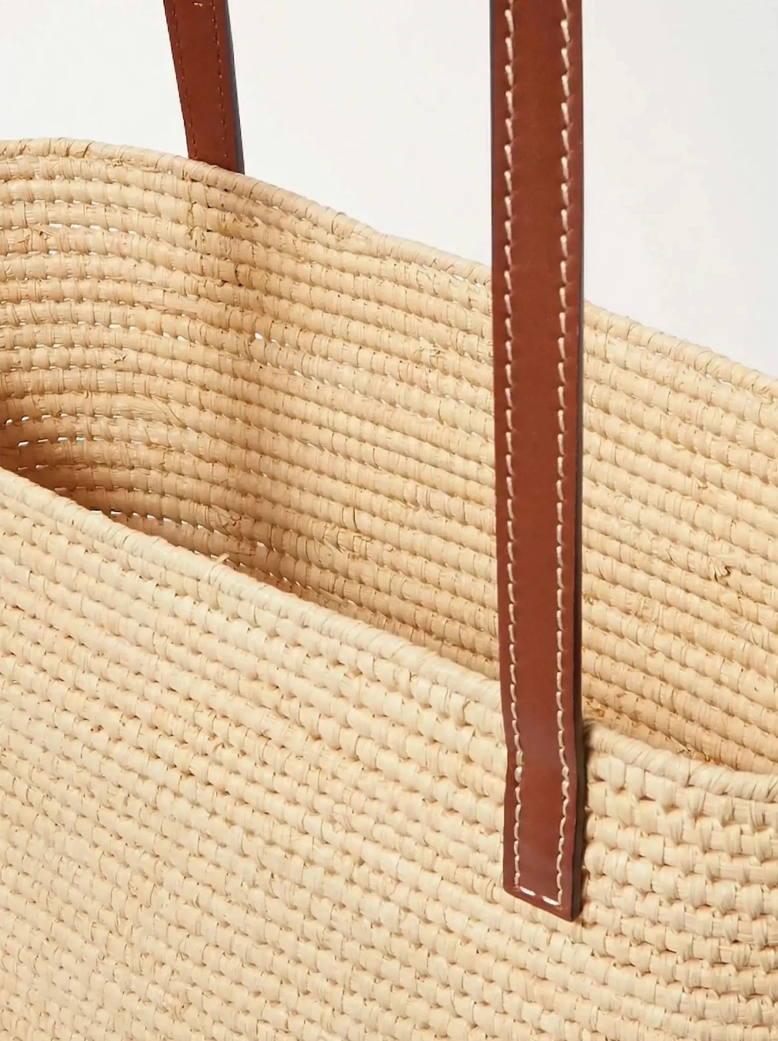 Close-up of the brown calfskin shoulder straps on the Yasmine Raffia Tote