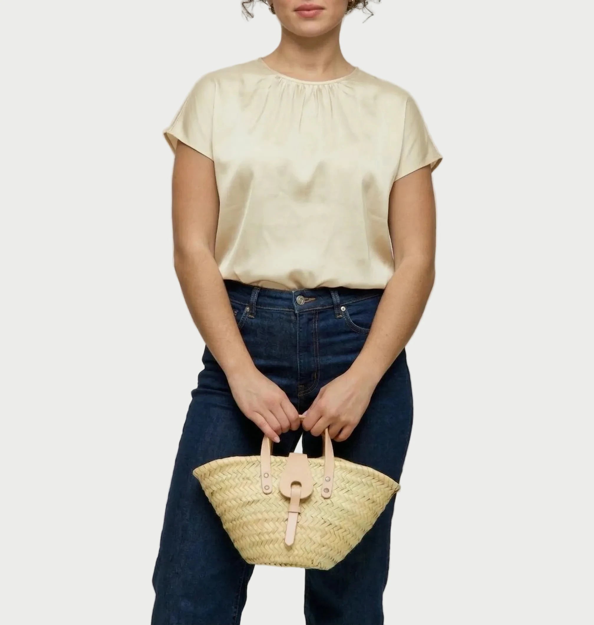 Woman holding the Zahira Mini palm leaf basket bag in natural calfskin