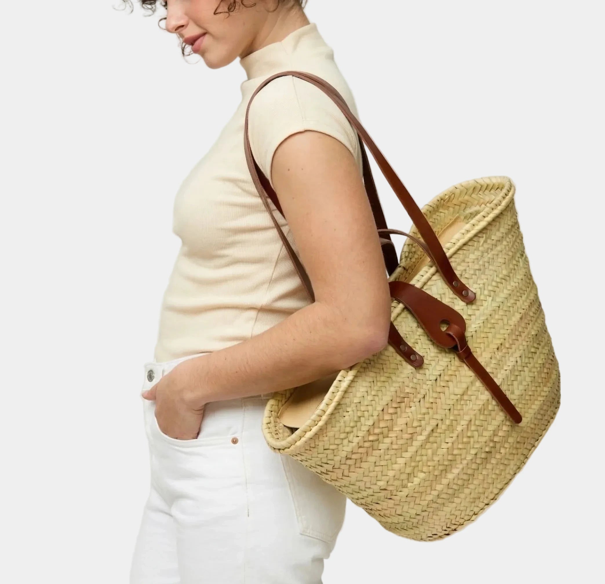 Woman carrying the Zhour Large palm leaf basket bag in dark brown calfskin on the shoulder